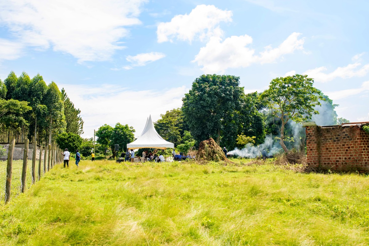 Open, fenced land at a FortuneVille estate with visitors under a tent in the distance